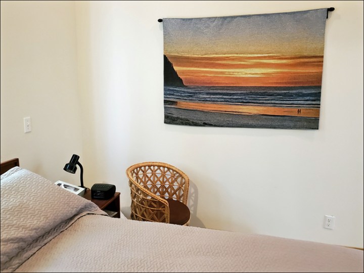 A picture of my bedroom wall with a sunset tapestry made from one of my photos.